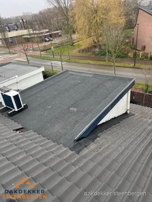 Plat dak met bitumen dakbedekking naast schuin pannendak in Steenbergen
