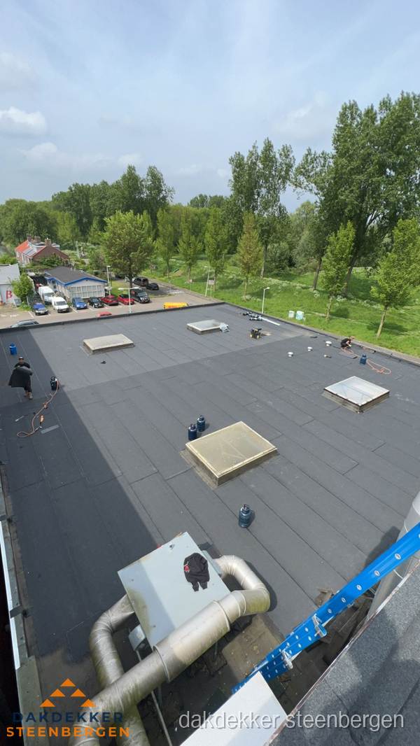 Dakdekker aan het werk op groot plat dak met bitumen in Steenbergen