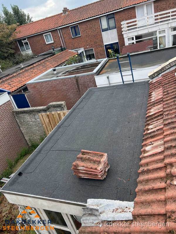 Plat dak aanbouw met bitumen naast schuin pannendak in Steenbergen