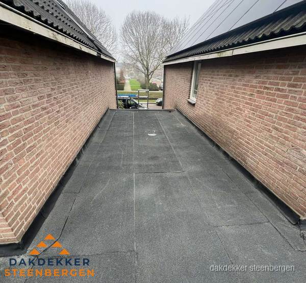 Plat dak met bitumen dakbedekking tussen bakstenen muren in Steenbergen