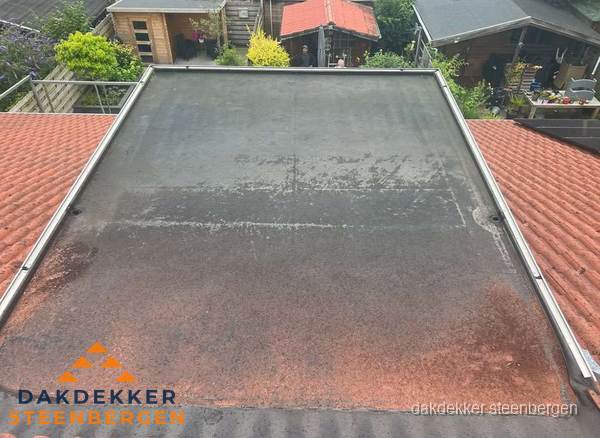 Verouderd plat dak met slijtage tussen schuine daken in Steenbergen Verouderd plat dak met slijtage tussen schuine daken in Steenbergen