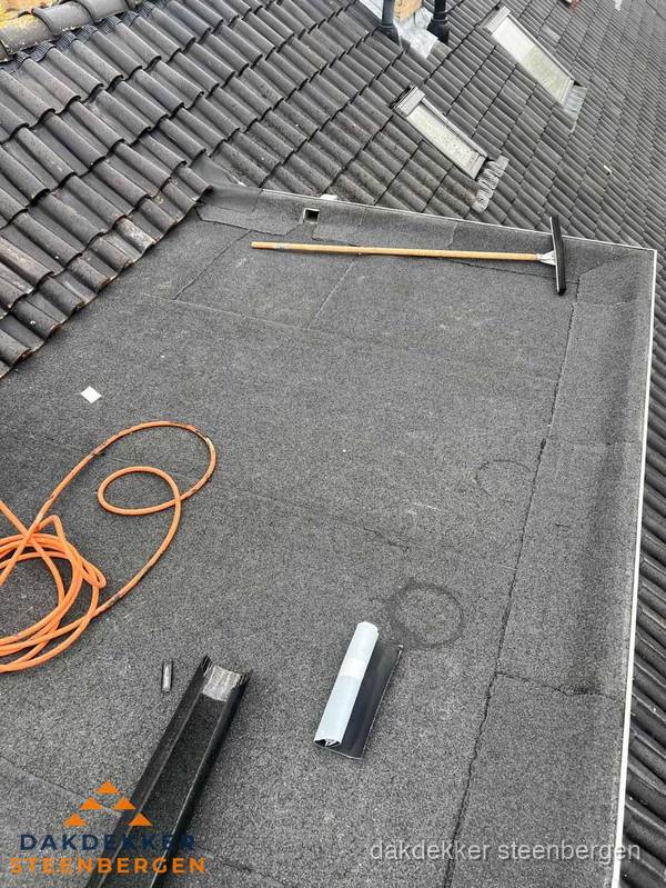 Plat dak reparatie met gereedschap en loodstroken in Steenbergen